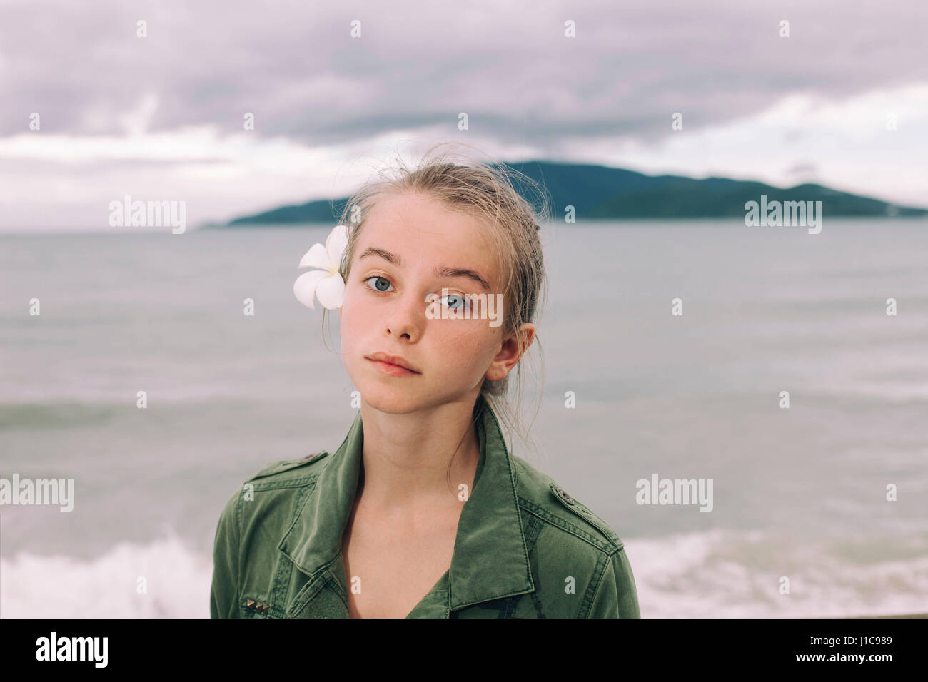 Kaukasische Frau mit Blume im Haar in der Nähe von Meer Stockfoto