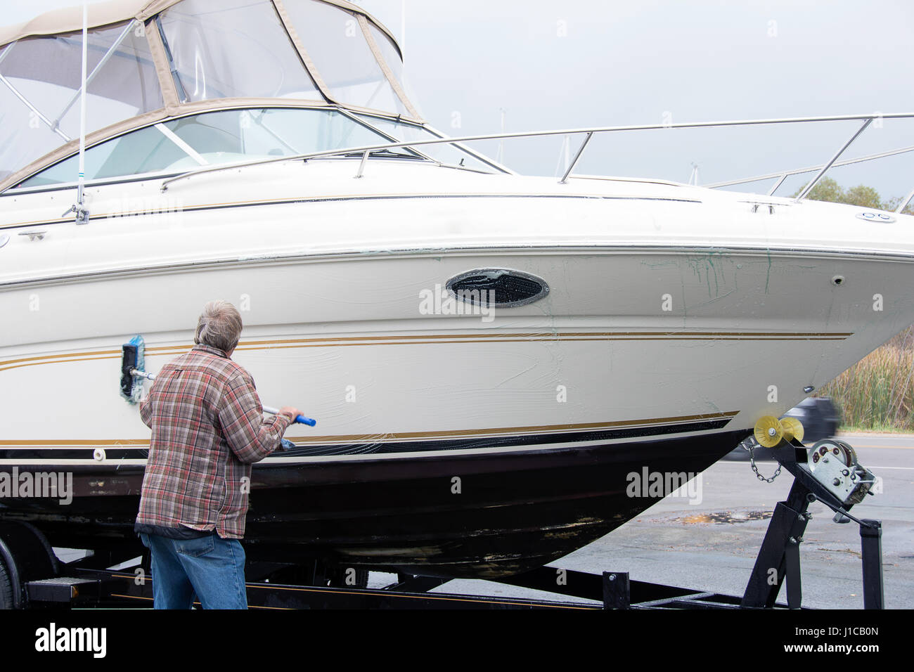 Mann Waschen Motorboot mit Pinsel Stockfoto