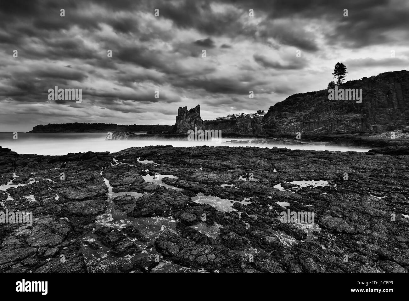 Schroffe Küsten Felsformation in der Nähe von Bombo Strand von Kiama Pacific Shore bei Sonnenuntergang. Berühmte Kathedrale Felsen aus Sandstein in schwarz-weiß umgewandelt. Stockfoto