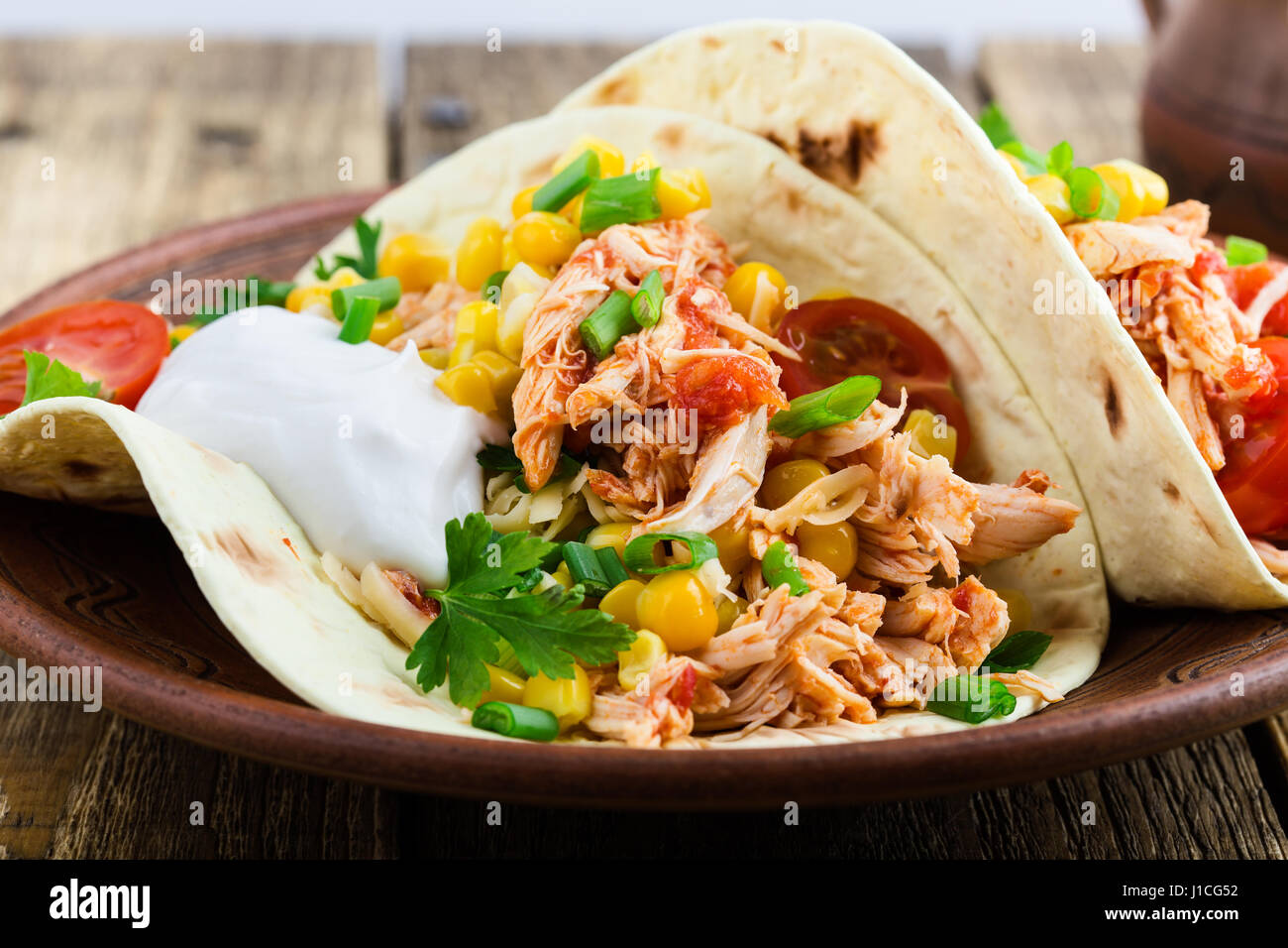 Hausgemachte langsame Herd Chicken Taco mit Mais auf rustikale Keramik-Platte auf Holztisch, mexikanischen Stil serviert Stockfoto
