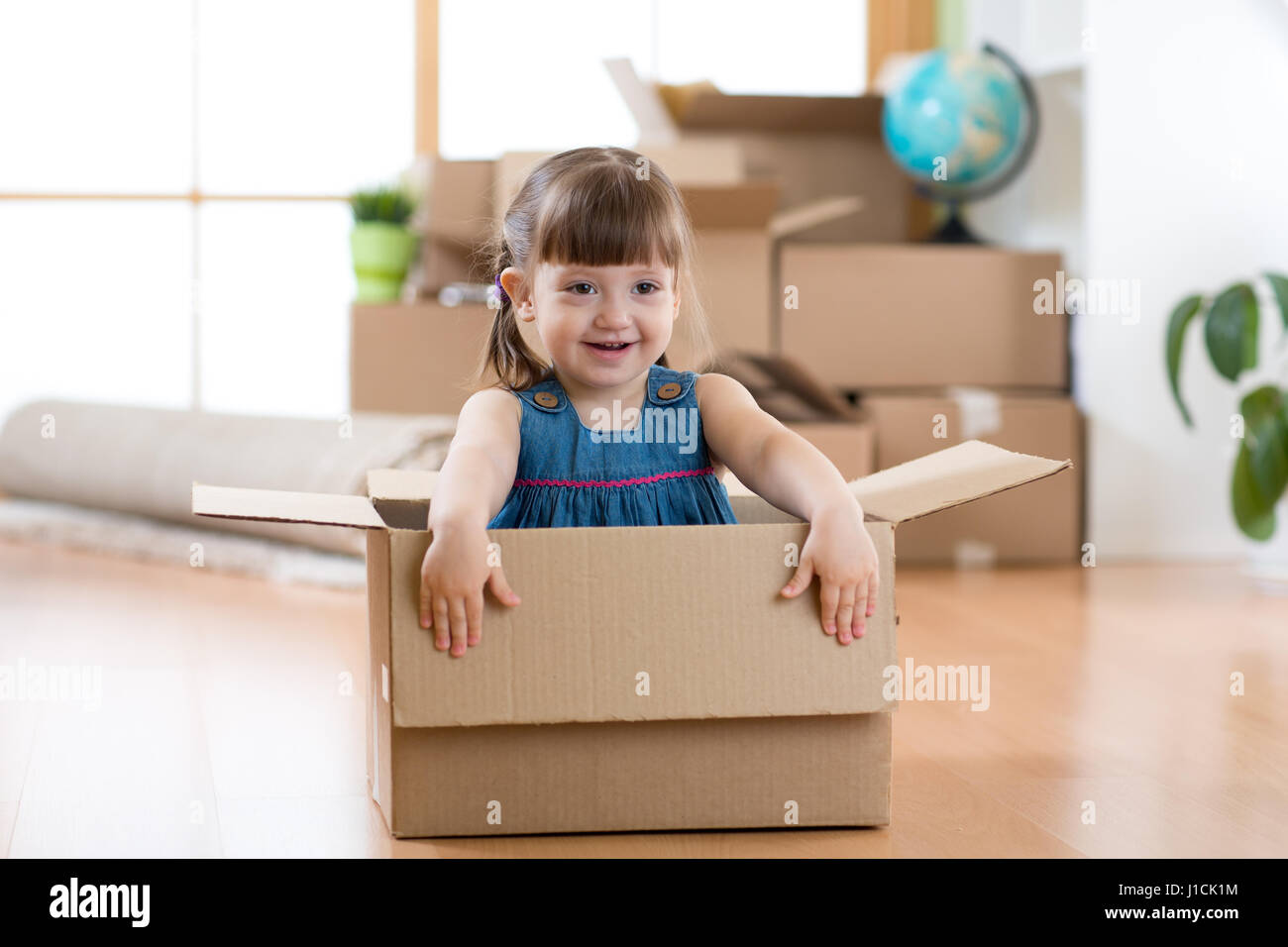 Umzug in neue Wohnung. Glückliches Kind im Karton. Stockfoto