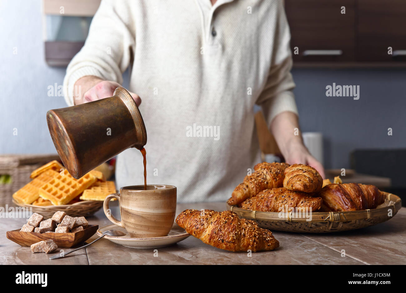 Frühstück mit Croissants, schwarzen Kaffee und frisch gebackenen Waffeln. Alte Kupfer Kaffeemaschine. Frischer heißer Kaffee in die Tasse gegossen. Stockfoto