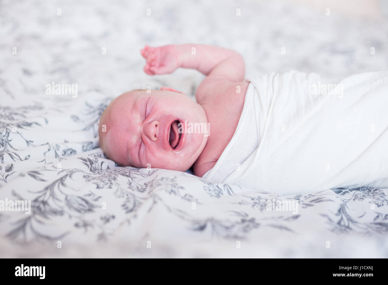 Neugeborenes Baby im Bett Weinen. Natürliches Licht, geringe Schärfentiefe, Textfreiraum. Stockfoto