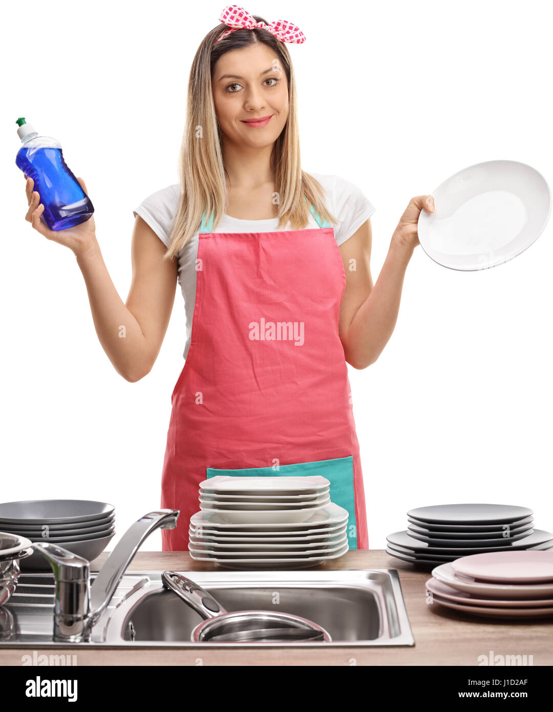 Junge Frau mit Schürze halten ein Reinigungsmittel und einen sauberen Teller isoliert auf weißem Hintergrund Stockfoto