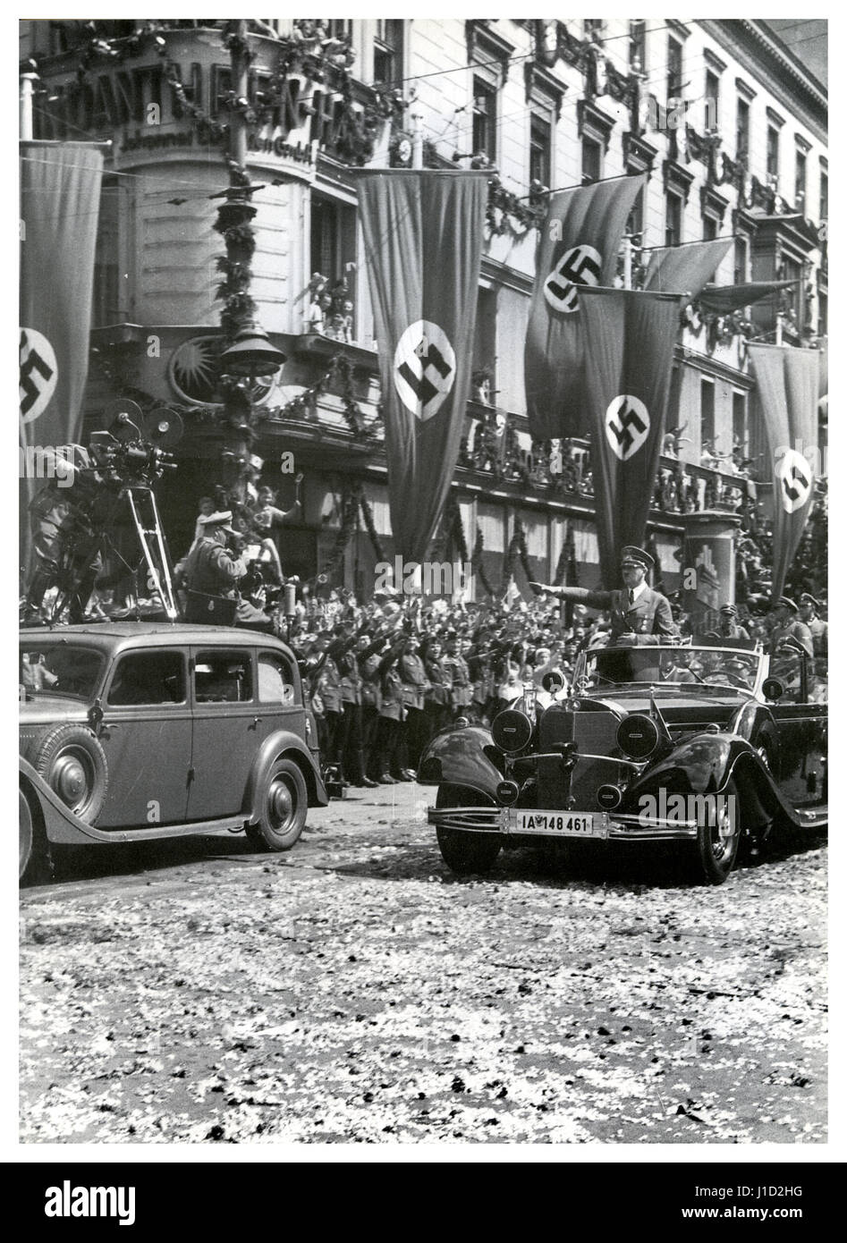 Führer Adolf Hitler kehrt am 4. Juli 1940 in einem offiziellen Mercedes im offenen Spitzenfeld in der klassischen "Sieg Heil"-Pose nach Berlin zurück, um nach seinem Besuch im vom Nazi besetzten Paris und seinem militärischen Erfolg in ganz Frankreich deutsche Menschenmassen, Nazi-Sturmtrupps, Blumenstreustraßen, Filmkameras und Swastika-Flaggen zu schmückern Stockfoto