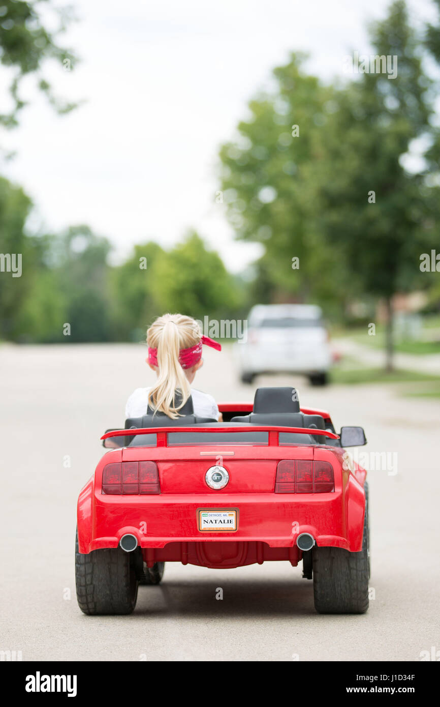 4 jährige blonde Mädchen fahren roten Mustang mit weiße Sonnenbrille und rotes Halstuch Stockfoto