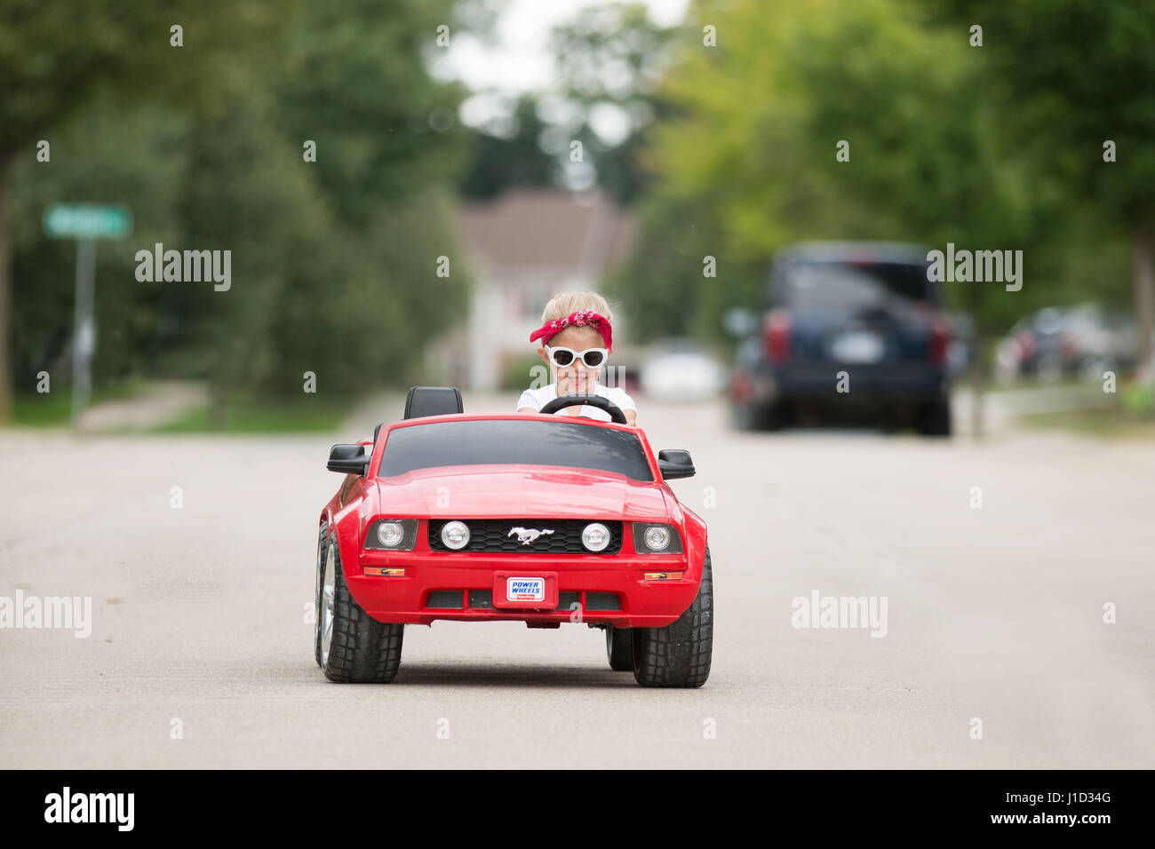 4 jährige blonde Mädchen fahren roten Mustang mit weiße Sonnenbrille und rotes Halstuch Stockfoto