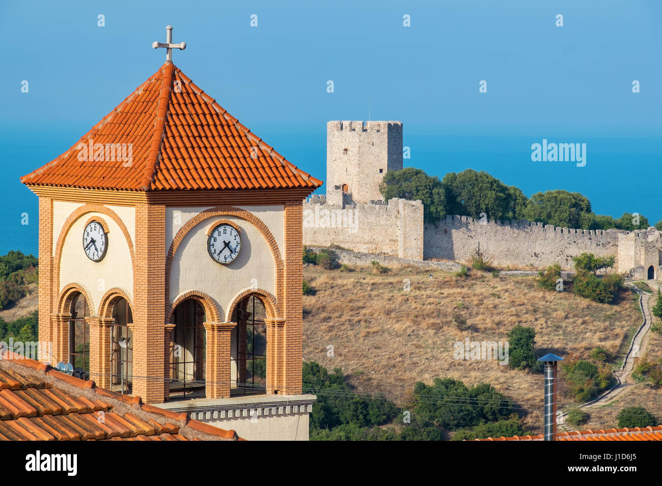 Glockenturm der Kirche von Agios Eleftherios in Neos Panteleimonas Dorf und mittelalterliche Festung Platamonas in der Entfernung. Pieria, Mazedonien, Gr Stockfoto