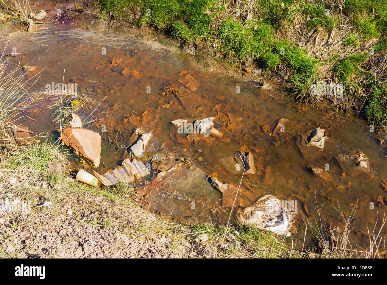 Verunreinigtes Wasser mit Müll und braunen Schlamm. Stockfoto