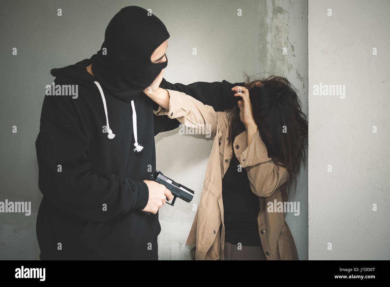 Geisel der Terrorist oder Einbrecher droht mit Waffe in verlassenen Gebäude Stockfoto