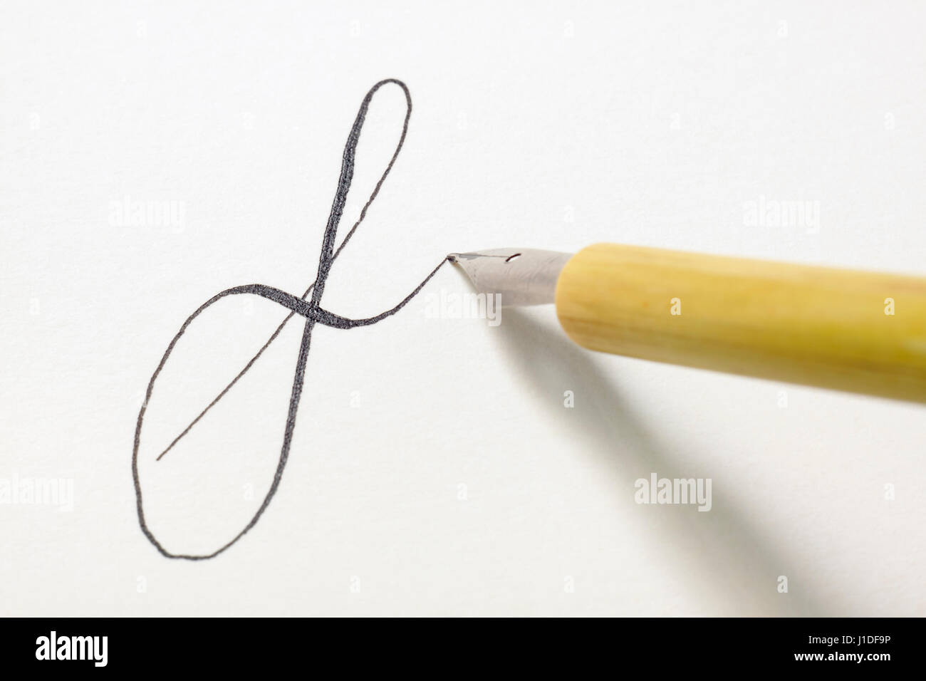 NIB-Stiftspitze Kleinbuchstabe f in einem spencerian Stil auf weißem Papier mit schwarzer Tinte zu schreiben Stockfoto