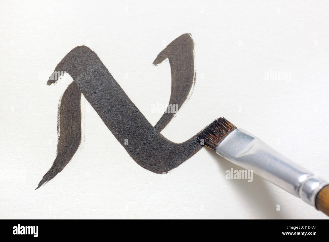 Flachpinsel-Tipp Schreiben N in einem Unzialen Stil auf weißem Papier mit schwarzer Tinte Stockfoto