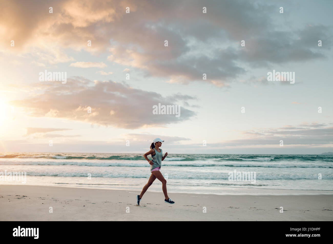 Im Freien Schuss junge Frau läuft entlang der Küste in Morgen. Fitness Frauen laufen Sport am Strand. Stockfoto