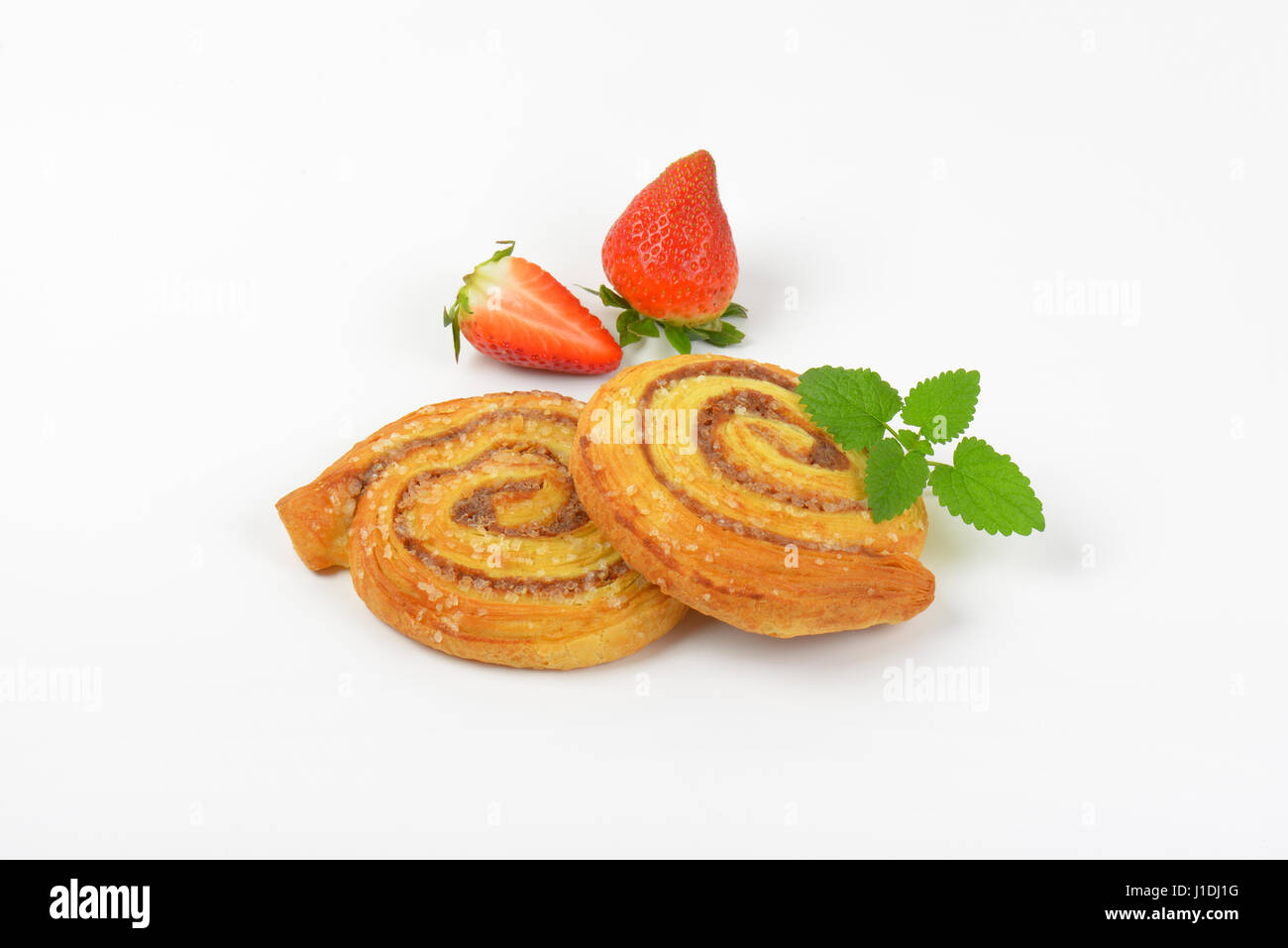süße Zimtschnecken und Erdbeeren auf weißem Hintergrund Stockfoto