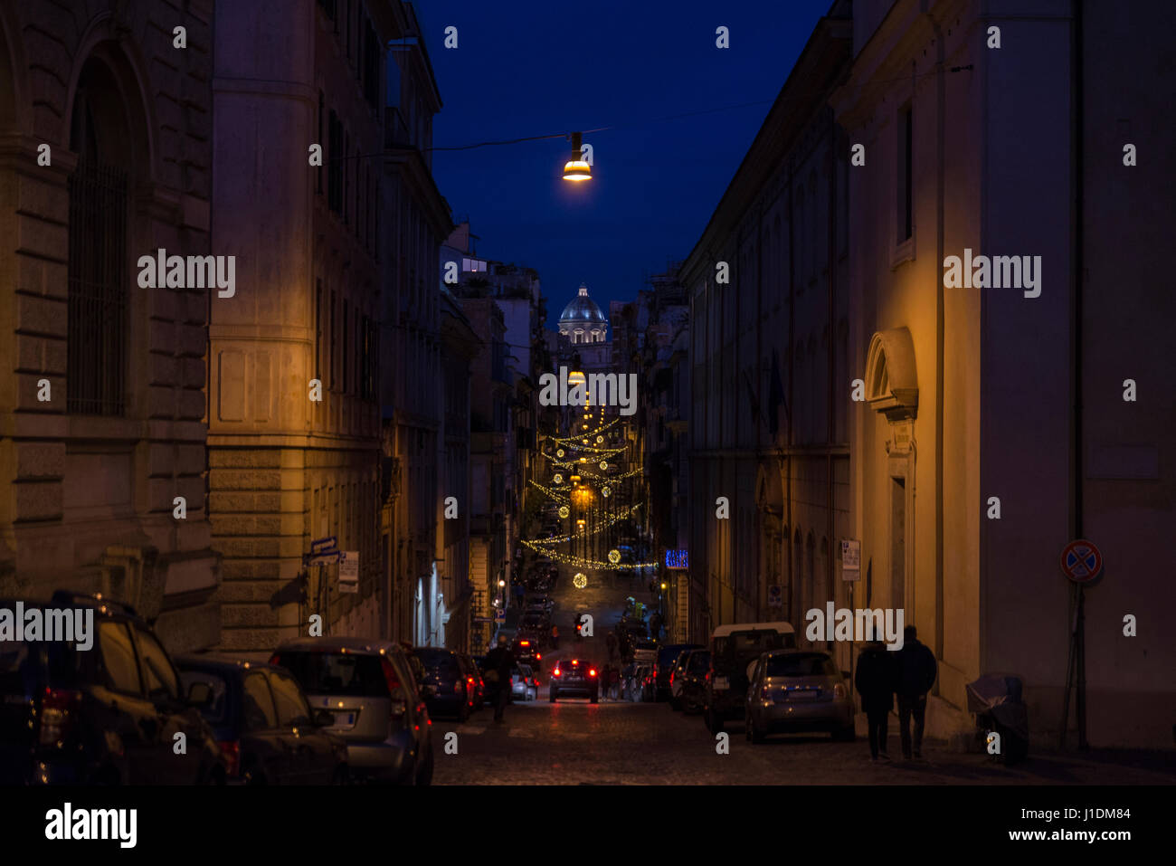 Weihnachtsbeleuchtung auf einer Straße in der Nacht mit Passanten in Rom, Italien Stockfoto