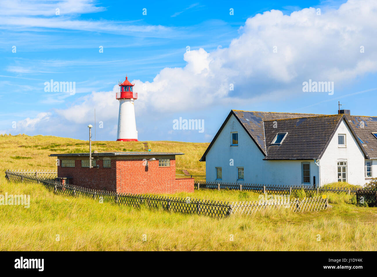 Häuser und Leuchtturm auf Sanddüne gegen blauen Himmel mit weißen Wolken auf der nördlichen Küste von Sylt Insel in der Nähe von Kampen Dorf, Deutschland Stockfoto