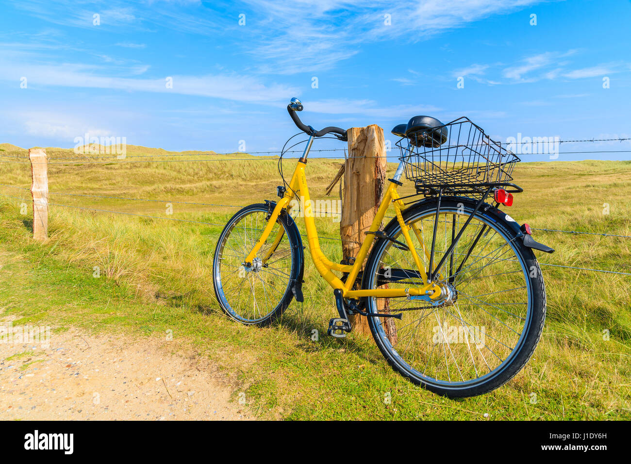 Insel SYLT, Deutschland - SEP 6, 2016: gelbe Fahrrad geparkt gegen einen Weidezaun in Landschaft Sylt Insel in der Nähe von Ellenbogen Strand, Deutschland. Stockfoto