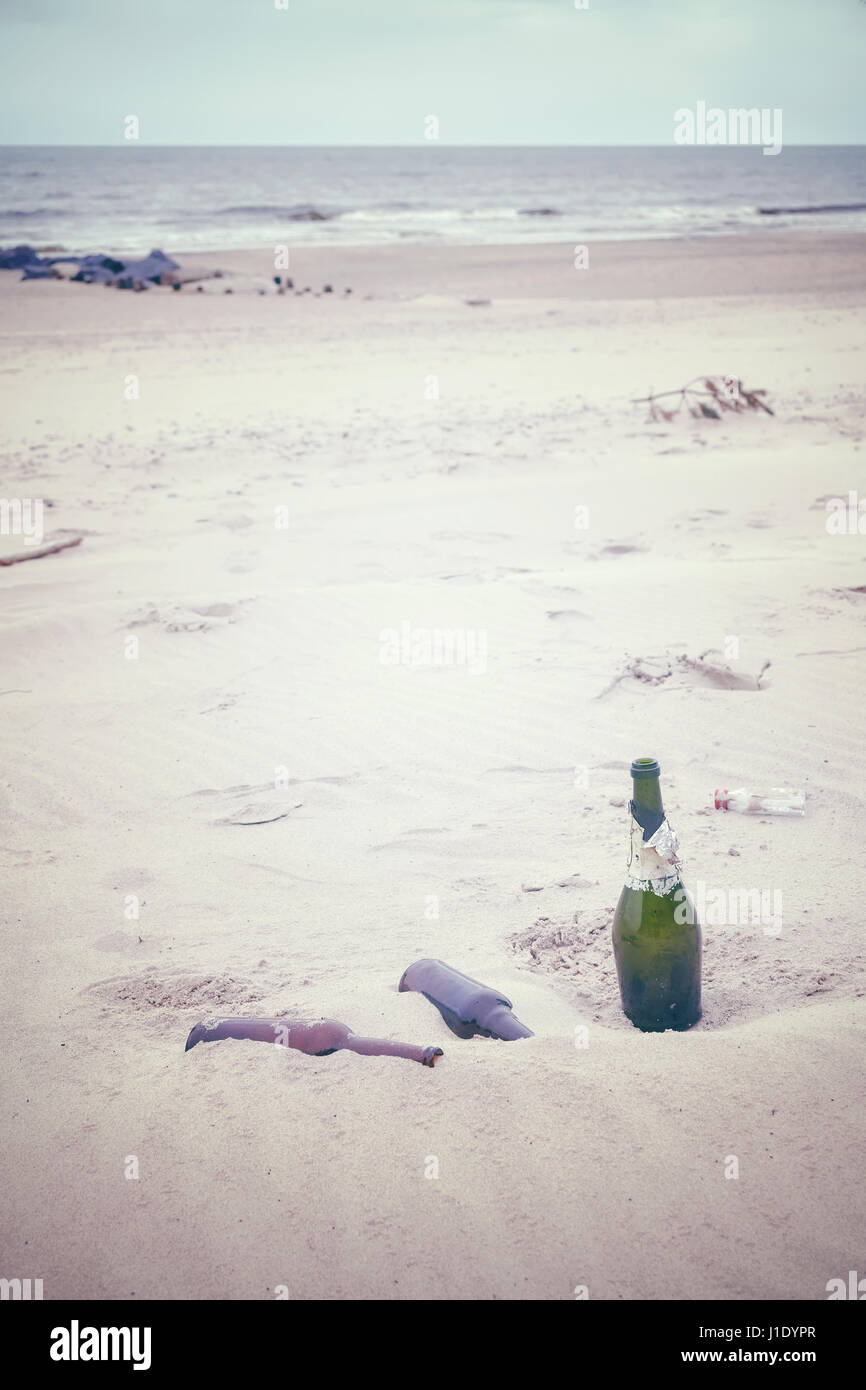 Getönten Farbfoto von leeren Schnapsflaschen an einem Strand, Umweltverschmutzung Konzept Bild links. Stockfoto