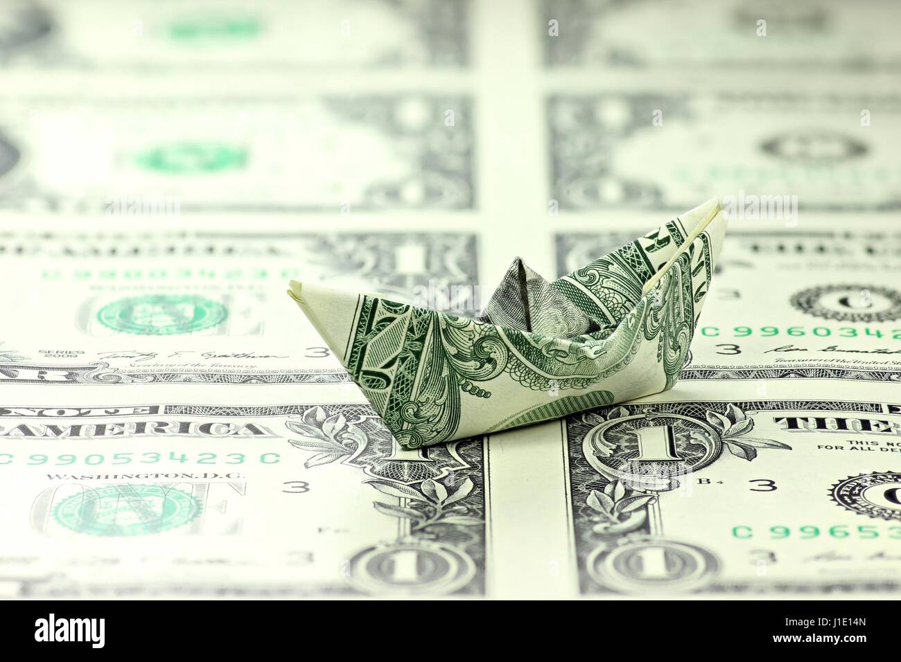 US-Dollar Papierschiff auf ungeschnittenen Blatt Stockfoto