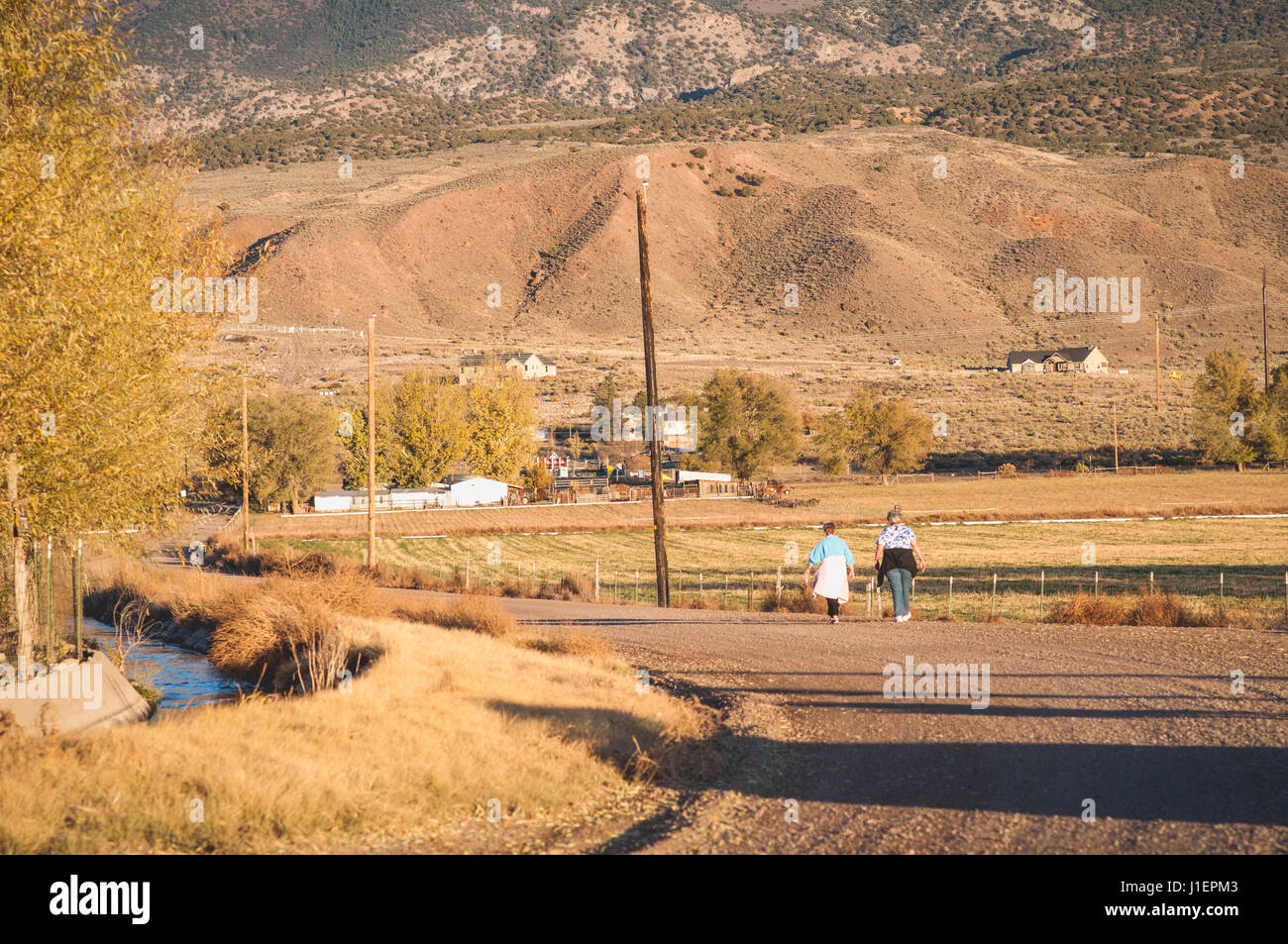 Zwei Frauen gehen auf einem Feldweg neben einem Kanal in ländlichen Utah. Stockfoto