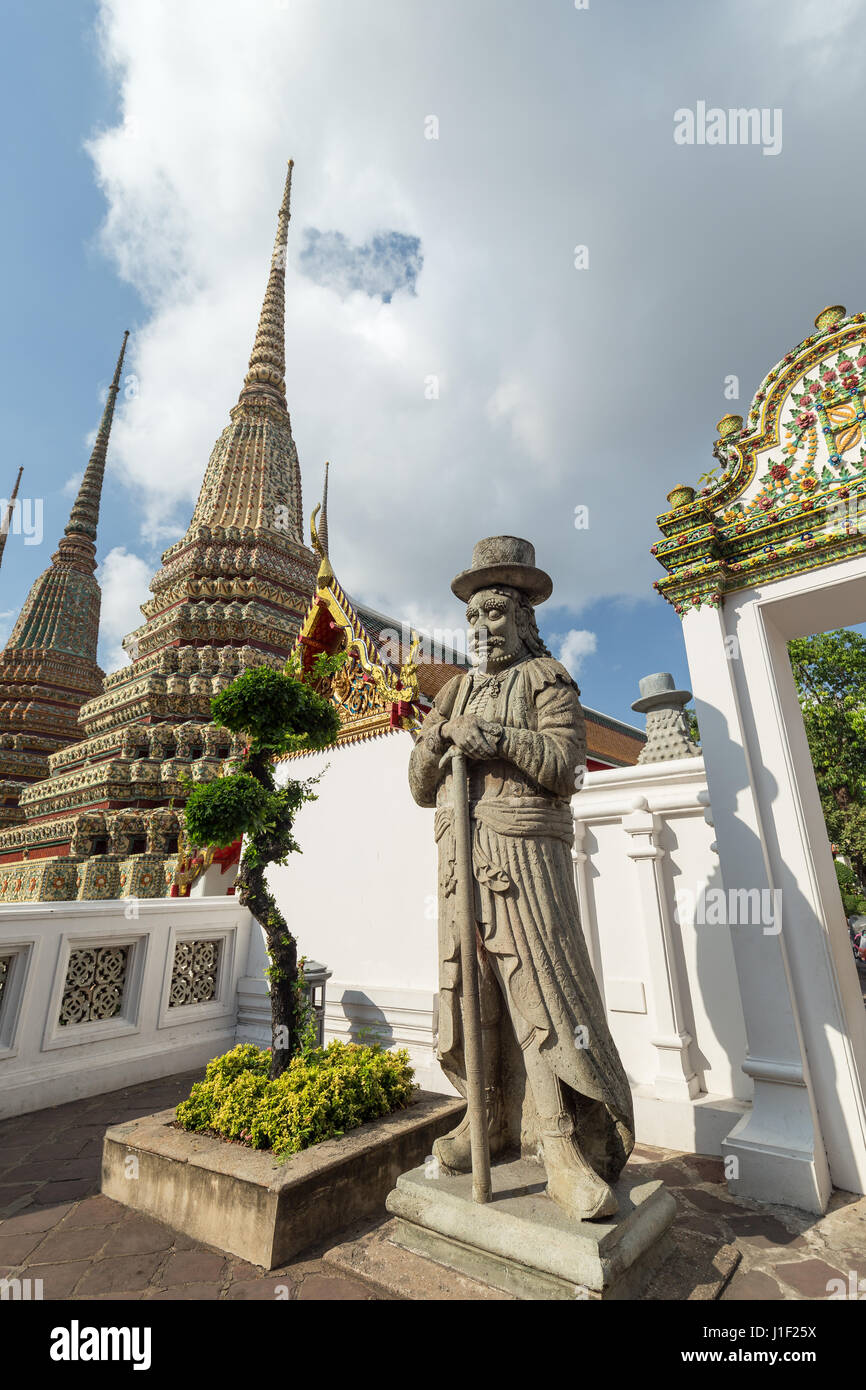 Eine große chinesische Statue, Baum und Chedis in der Tempelanlage Wat Pho (Po) in Bangkok, Thailand. Stockfoto