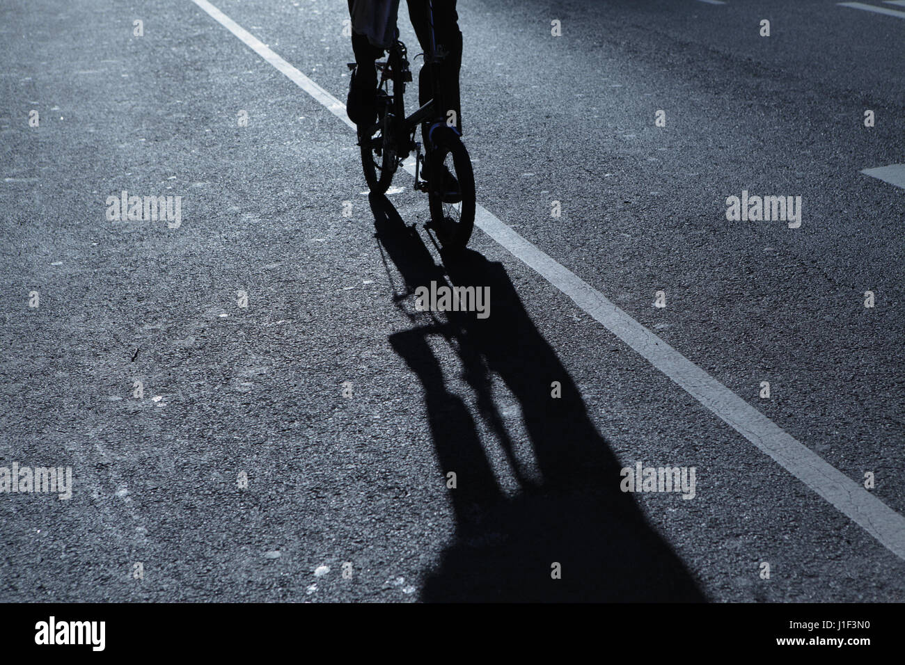 Abstrakter Begriff Silhouette eines unkenntlich Mann Radfahren kleinen fahrbaren Bike auf einer Straße in der Nacht in New York City. Blaue Nacht Schatten Reihe. Stockfoto