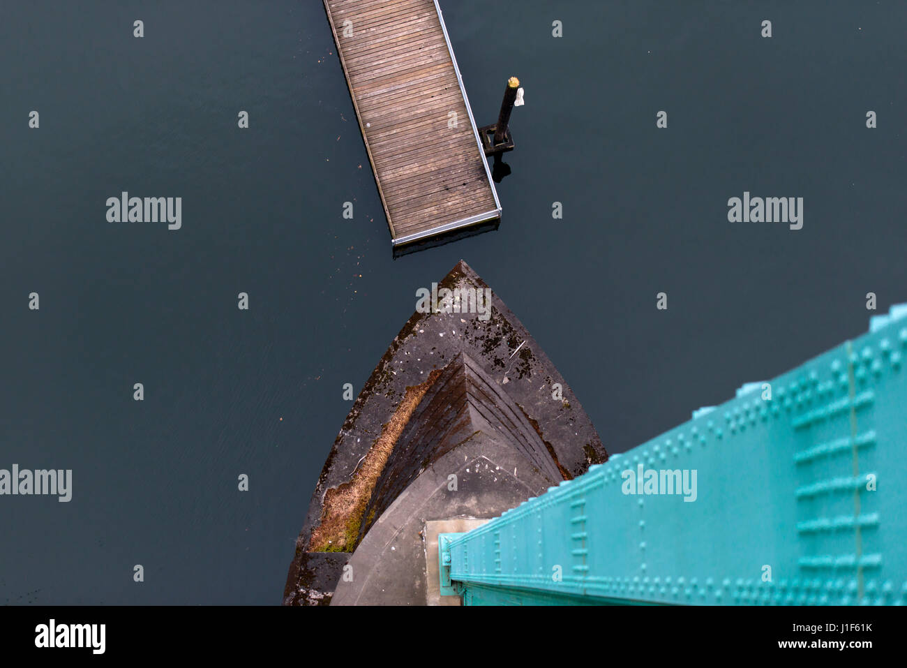 Moderne Top Aussicht auf die grünen Unterstützung und Betonfundament auf die Brücke, das dunkle Wasser und die hölzerne Pier mit einer restriktiven Spalte. Avantgarde Stockfoto