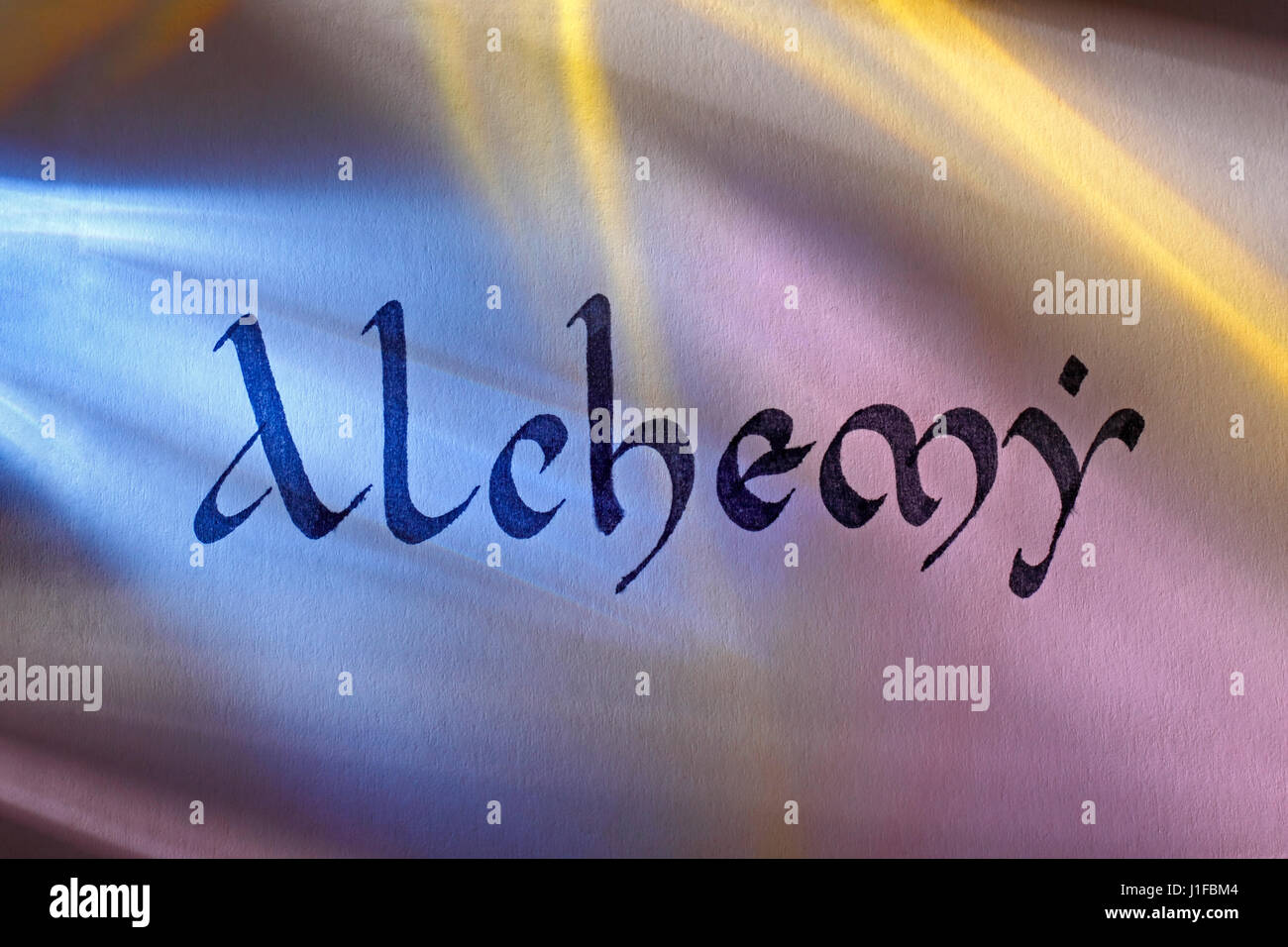 Handgeschriebene Wort Alchemie im mittelalterlichen Latein Skript unter bunten Lichtern. Englischer Sprache. Stockfoto