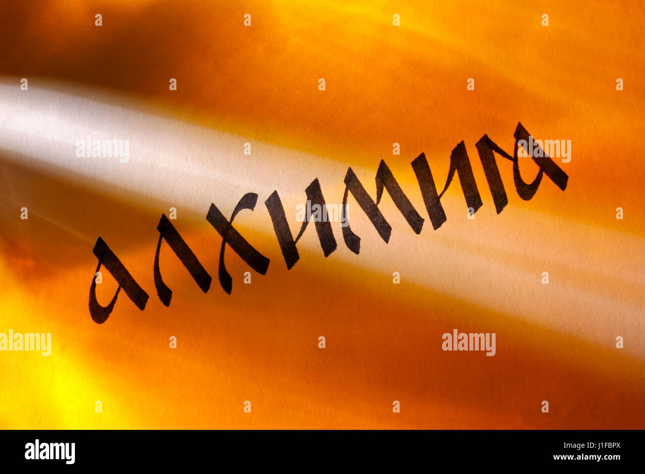 Handgeschriebene Wort Alchemie in kyrillischer Schrift unter bunten Lichtern. Russische Sprache. Stockfoto