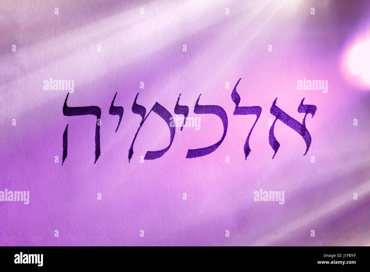 Handgeschriebene Wort Alchemie in hebräischer Schrift unter bunten Lichtern. Hebräische Sprache. Stockfoto