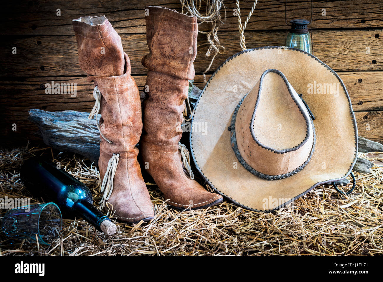 Stillleben mit amerikanischen Westens Rodeo braunen Filz Cowboy-Hut und traditionellen Lederstiefel in Vintage Ranch Scheune Hintergrund Stockfoto