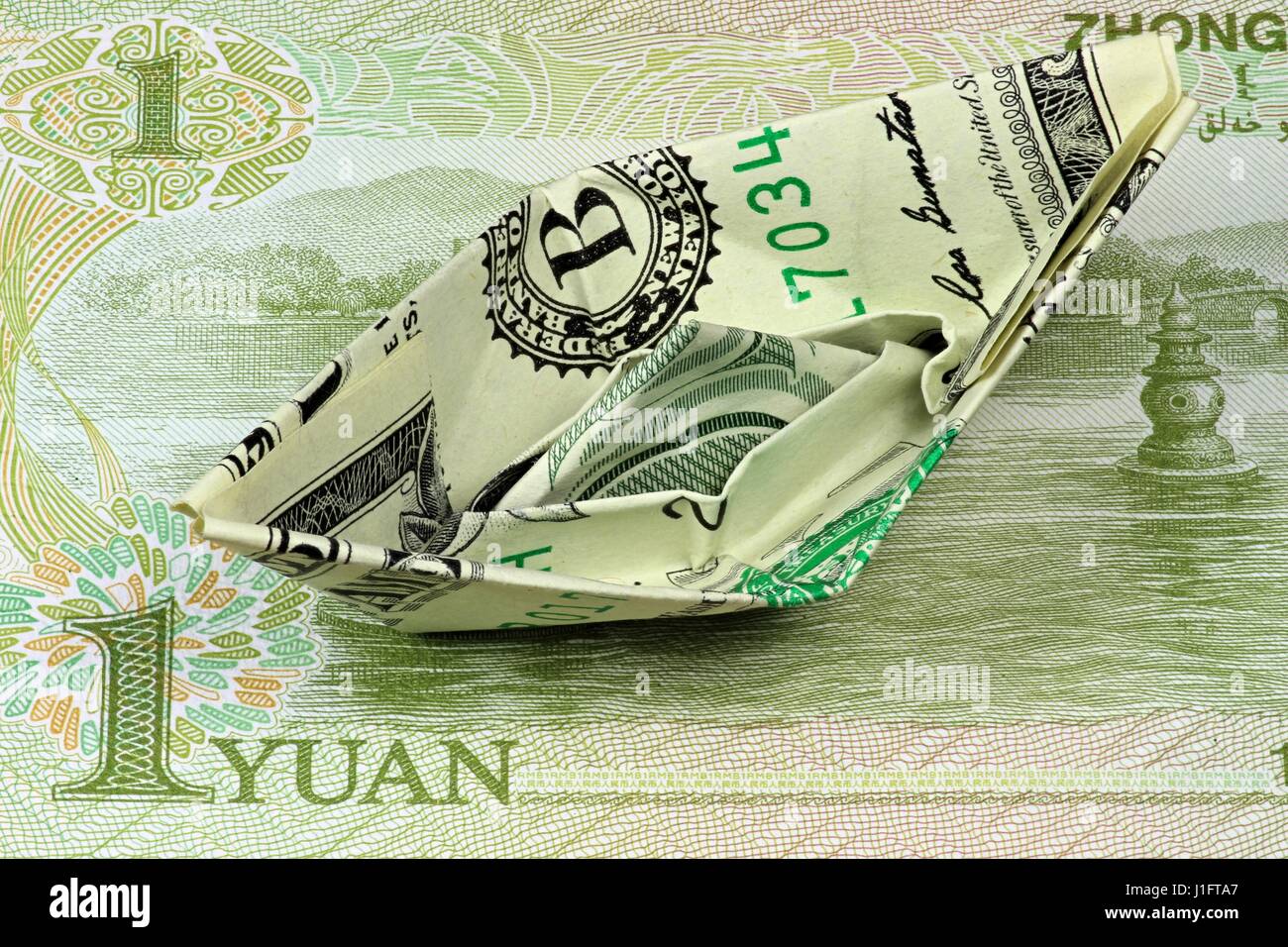 US-Dollar Papierschiff auf chinesische 1 Yuan note Stockfoto
