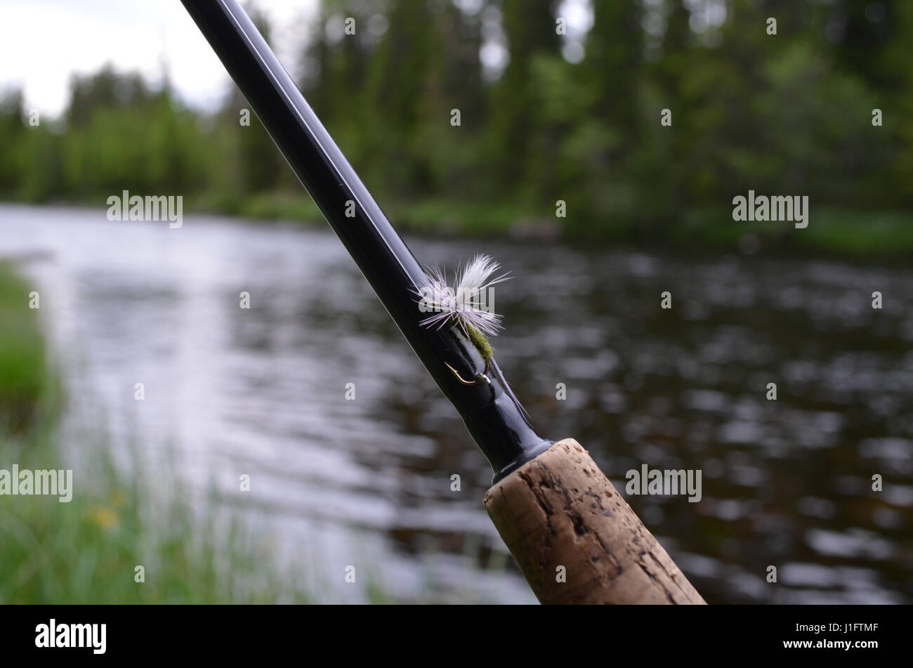 Trocken kann Nachahmung auf Fliegenrute gegen flachen Fluss fliegen. Stockfoto