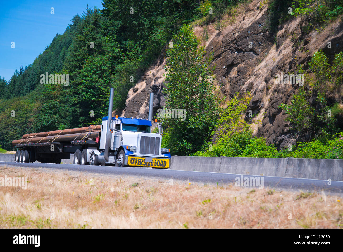 Spektakuläre klassische Sattelschlepper in Kombination von weißen und blauen Farbe mit den Zeichen übergroße Belastung Frontstoßstange übergroße Fracht transportiert Stockfoto