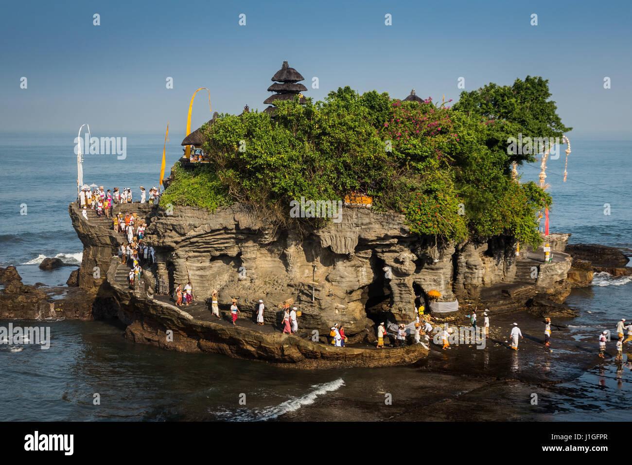Balinesische Hindus Pilgerfahrt nach Tanah Lot Felsentempel. Schöne Luftaufnahme von der berühmten Felsentempel empfangen viele Pilger in traditioneller Kleidung Stockfoto