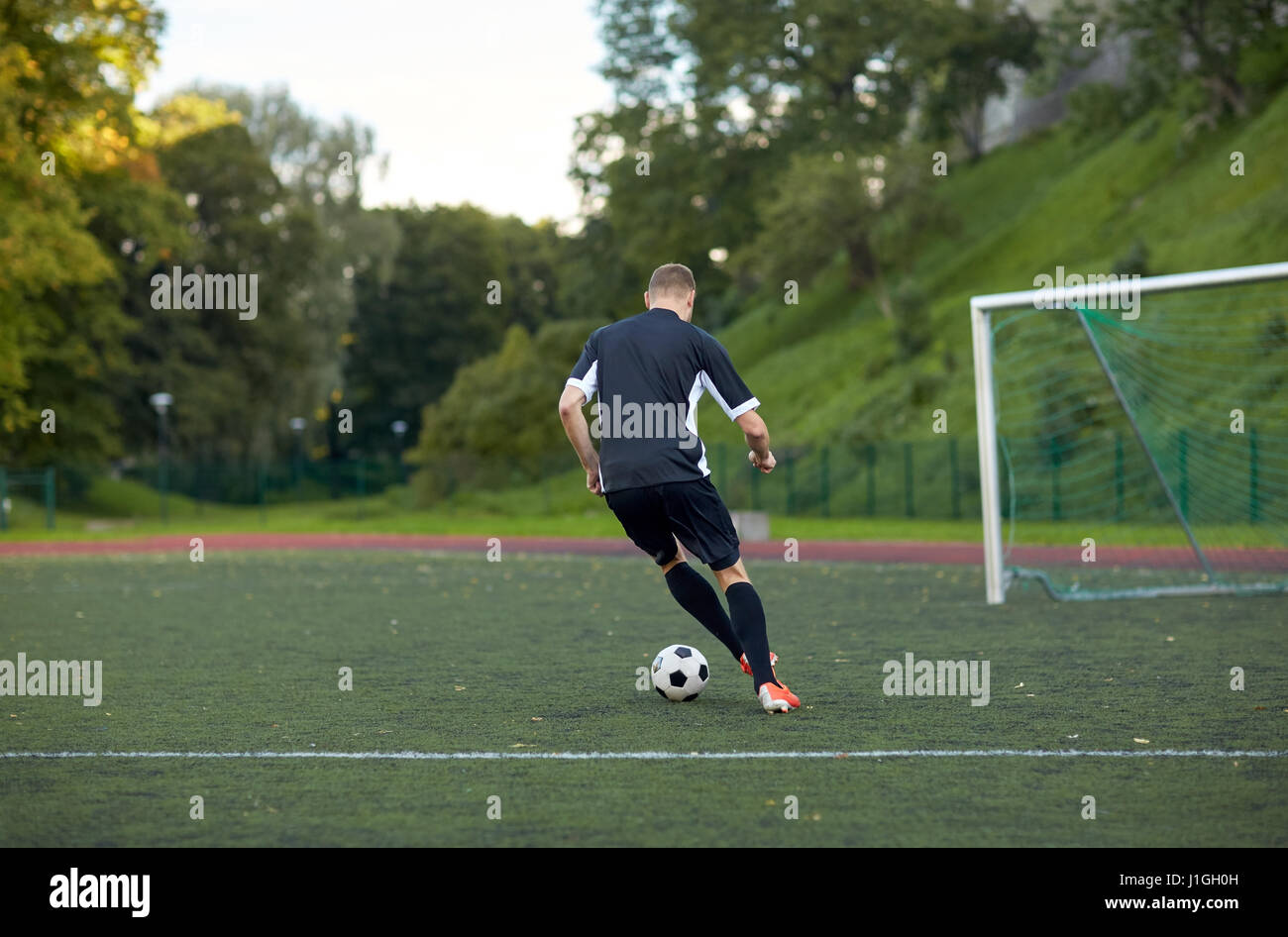 Fußballspieler mit Ball auf Fußballplatz spielen Stockfoto