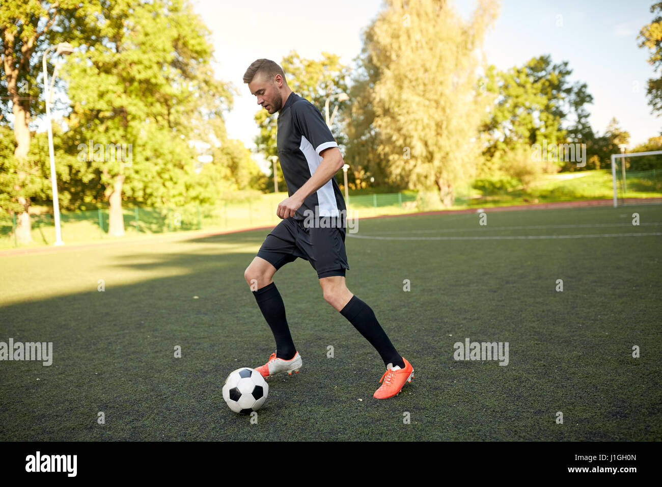 Fußballspieler mit Ball auf Fußballplatz spielen Stockfoto