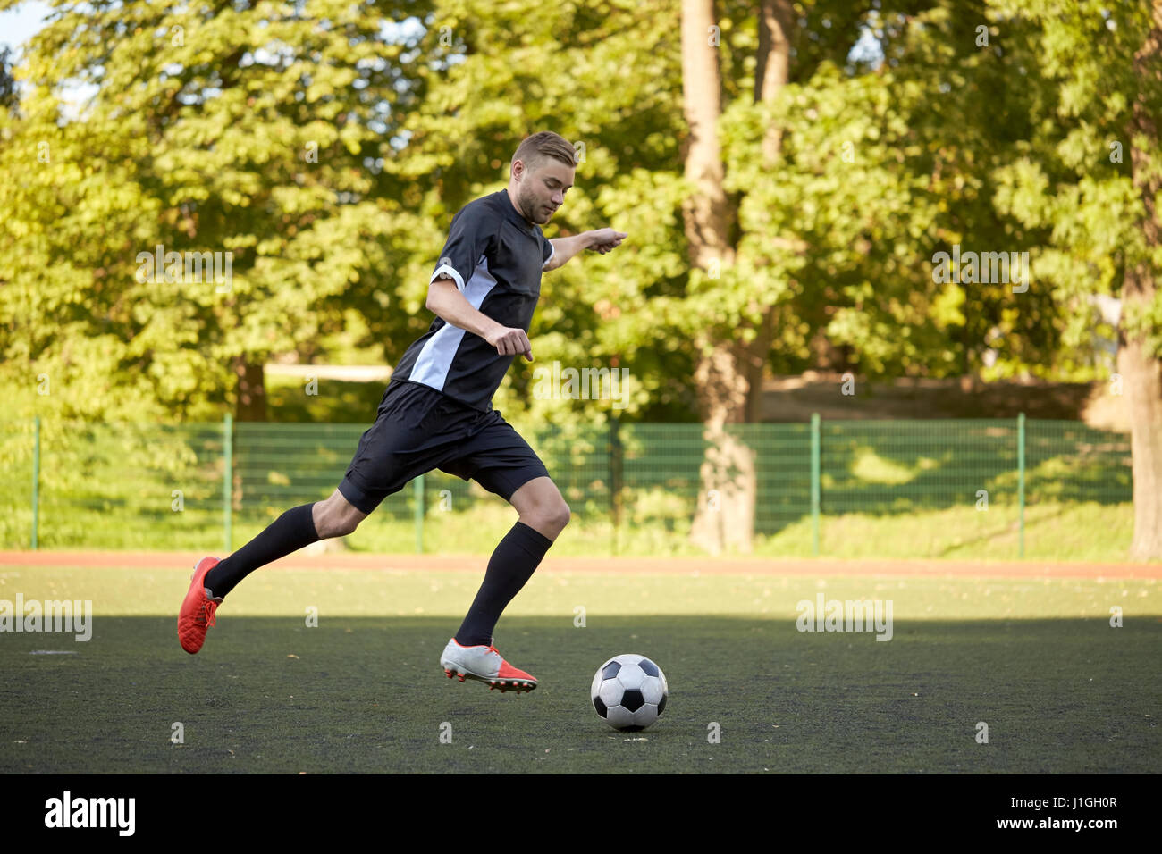 Fußballspieler mit Ball auf Fußballplatz spielen Stockfoto