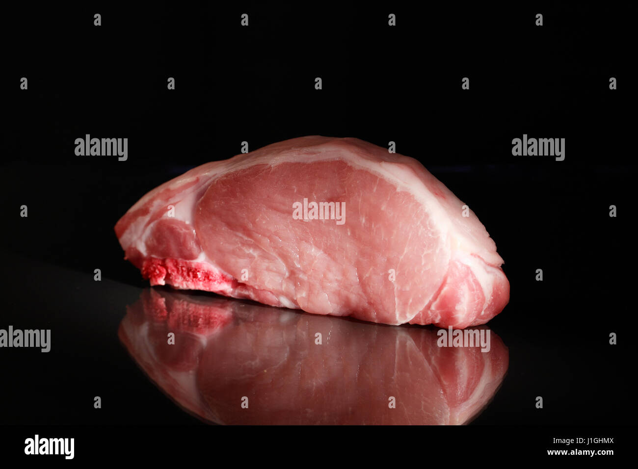 Frische Stück rohes Fleisch auf dunklem Glasoberfläche mit Reflexion Stockfoto