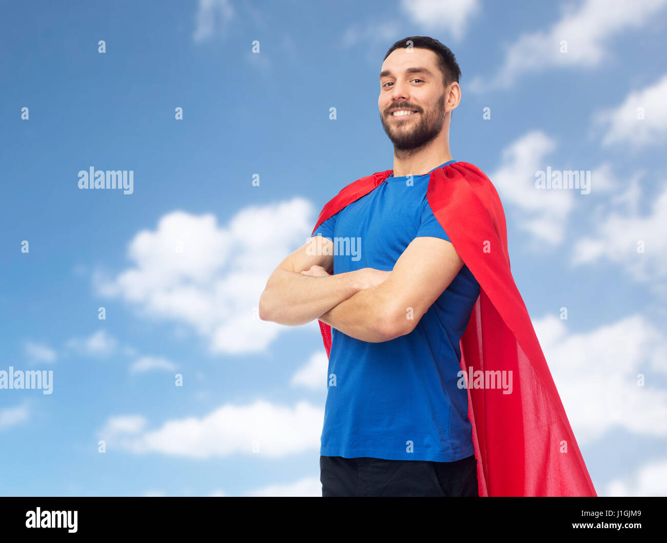 glücklicher Mann im roten Superhelden Cape über blauen Himmel Stockfoto
