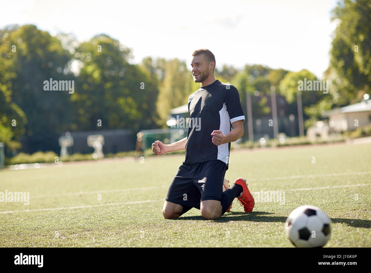 glücklich Fußballspieler mit Ball auf Fußballplatz Stockfoto