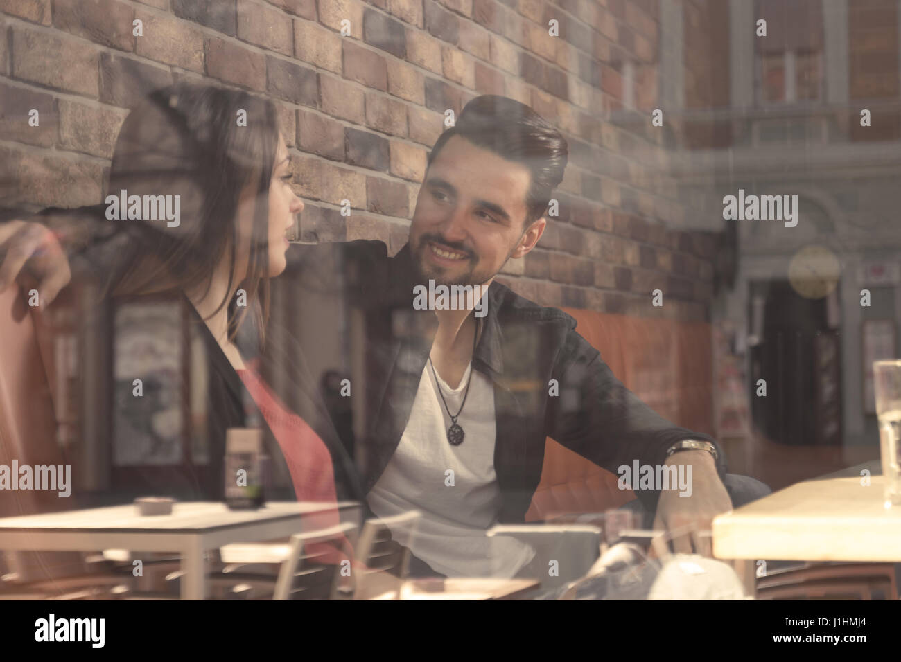 Café junge Erwachsene 20 s paar Freunde Frau Mann lächelnd Shooting dachte Fenster Reflexion im Gespräch Stockfoto