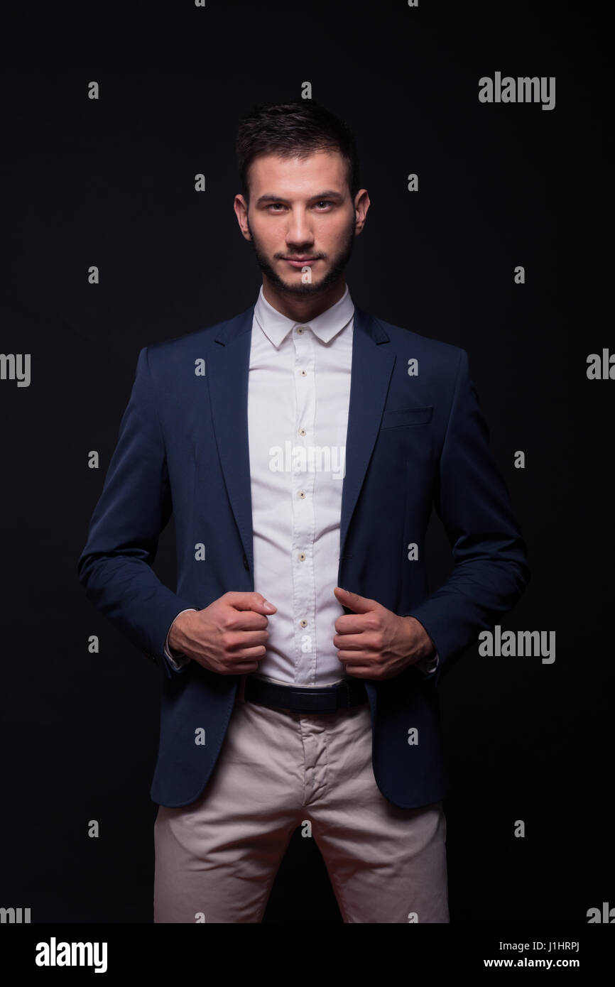 junger Erwachsener Mann Modell elegantes Hemd Hosenanzug, blaue Jacke,  schwarzer Hintergrund halten Stockfotografie - Alamy