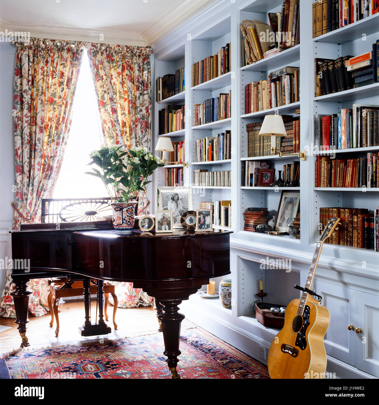 Klavier und Gitarre neben Bücherregal. Stockfoto