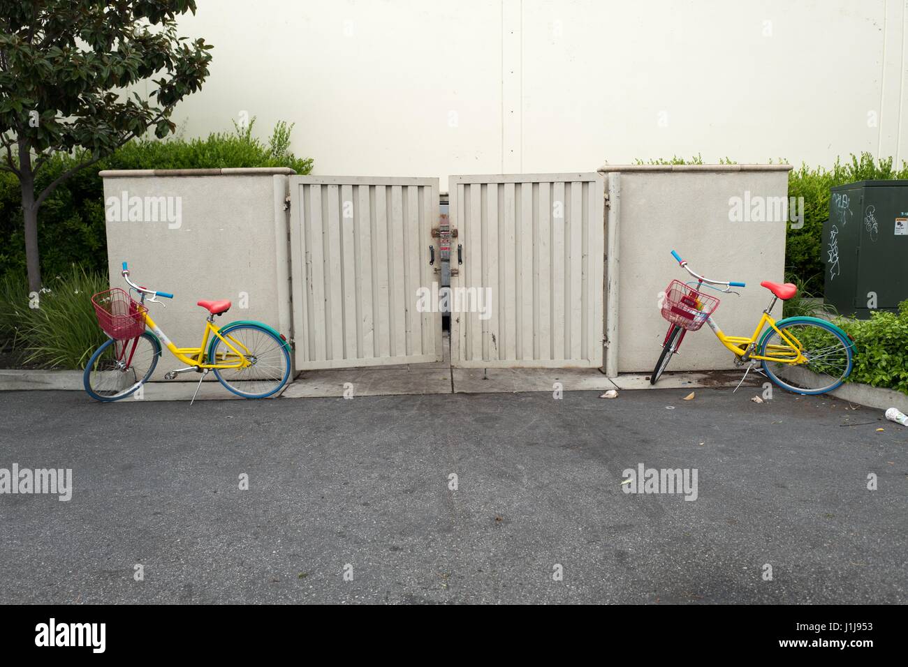 Zwei Google-Fahrräder sind zufällig parkten in der Nähe ein Müll Müllcontainer in der Nähe der Googleplex Silicon Valley Sitz der Suchmaschine und Technologie Unternehmen Google Inc., Mountain View, Kalifornien, 7. April 2017. Stockfoto