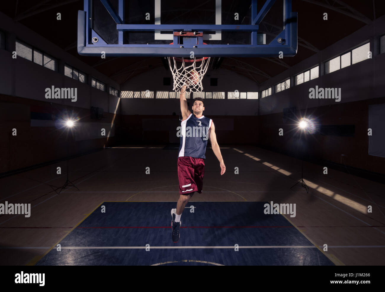 ein junger Erwachsener Mann, Basketball-Spieler Dunk in Luft, Slam Dunk, drinnen dunkel Basketballplatz Stockfoto