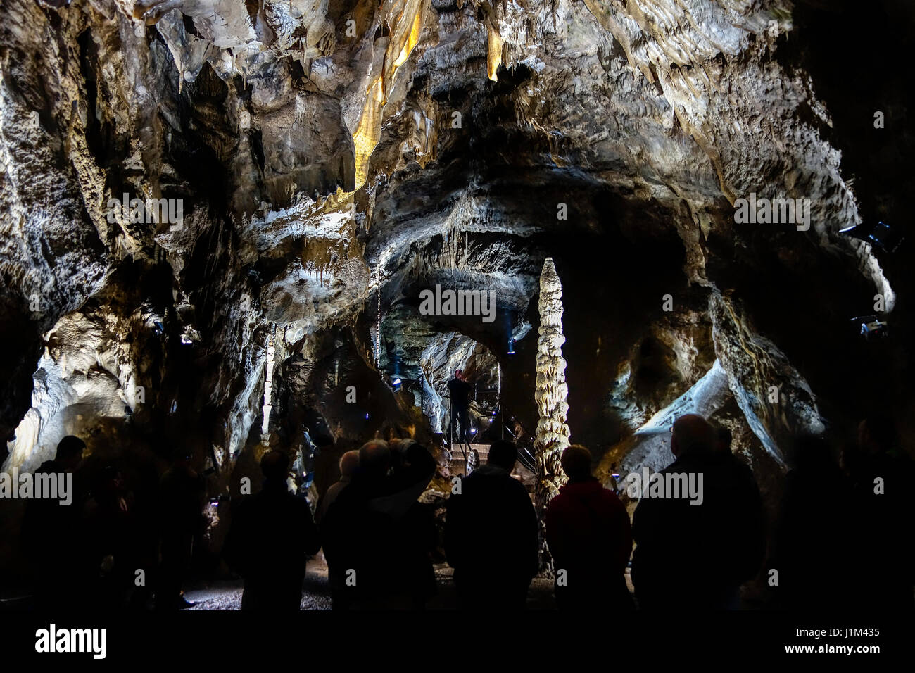 Touristen, die gerne an großen Stalagmiten während der Führung in den Höhlen von Han-Sur-Lesse / Grottes de Han, belgische Ardennen, Belgien Stockfoto