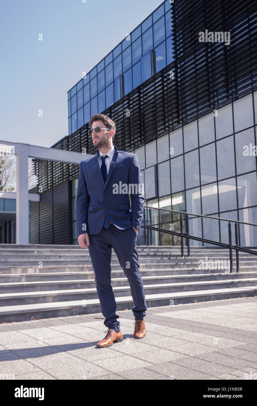 ein junger Mann zu Fuß Anzug Krawatte, moderne Gebäude-Architektur, Hand in der Tasche Stockfoto