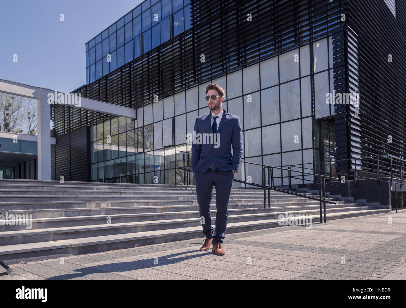 ein junger Mann, Anzug, Krawatte, moderne Gebäude-Architektur, wandern die Hände in den Taschen Stockfoto