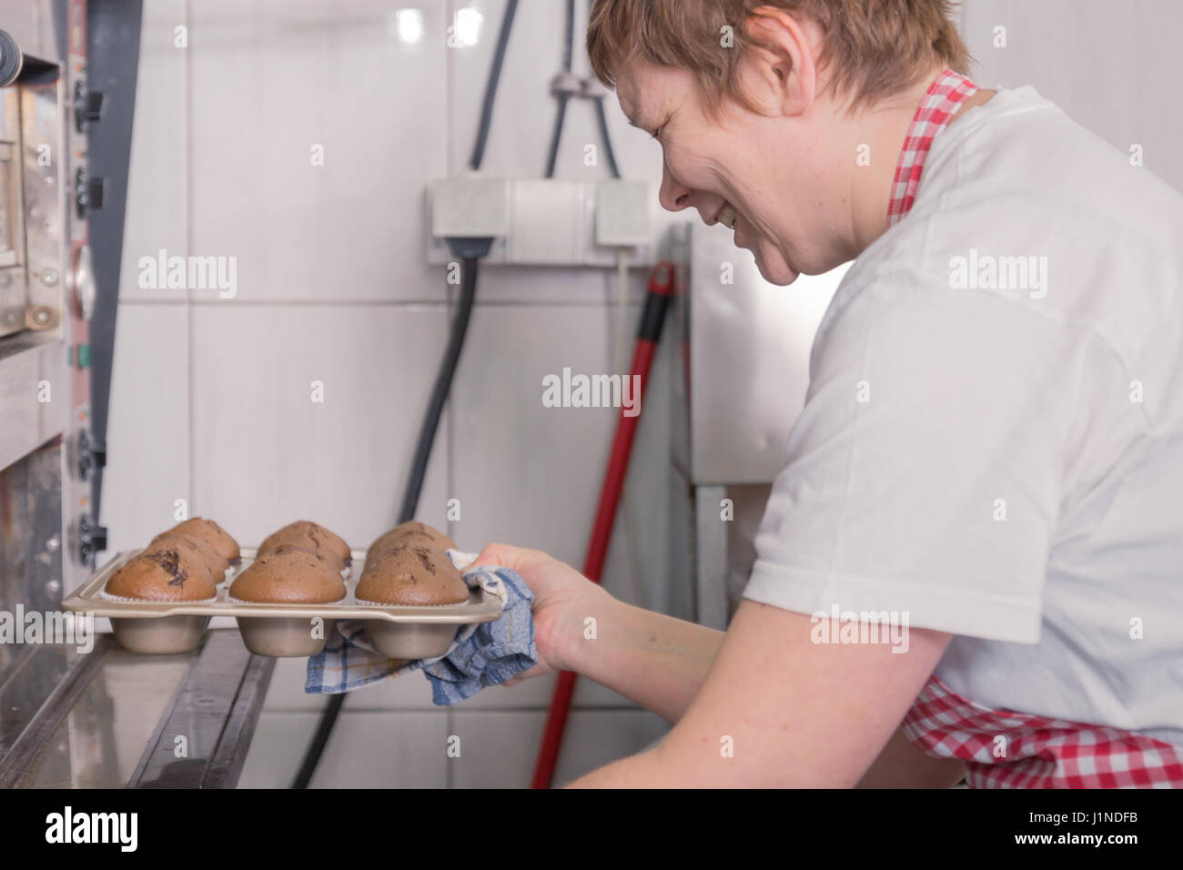 glücklich lächelnd eine reife Frau Closeup Frau Ofen Kochen fertig gemacht Muffins, Seitenansicht, Großküchen Stockfoto